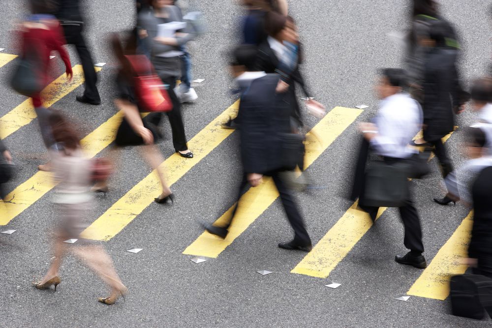Many pedestrians walking in opposite directions across street